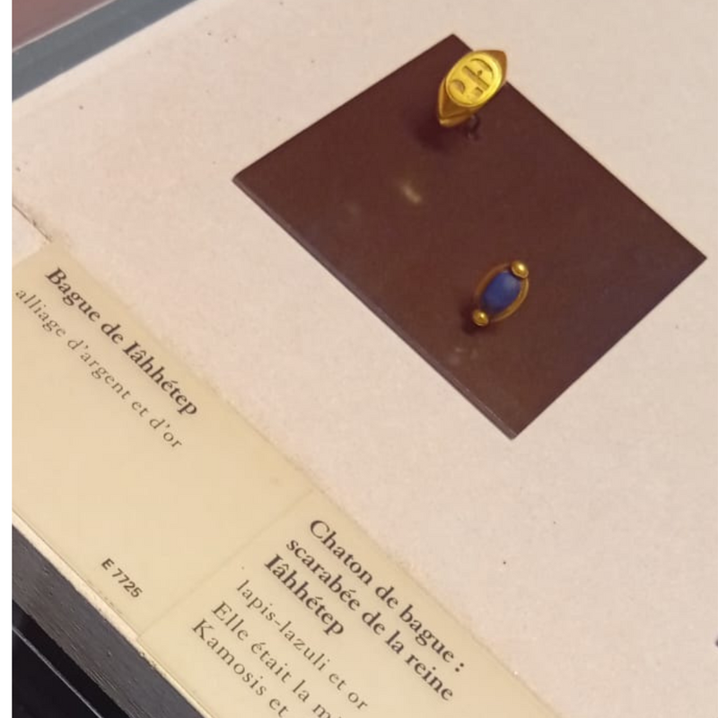 Louvre display of a ring  in gold and silver (left) and lapis-lazuli blue bettle ring, which are not dissimilar to those of Queen Iâhhotep and mother of Kamosis and Amosis